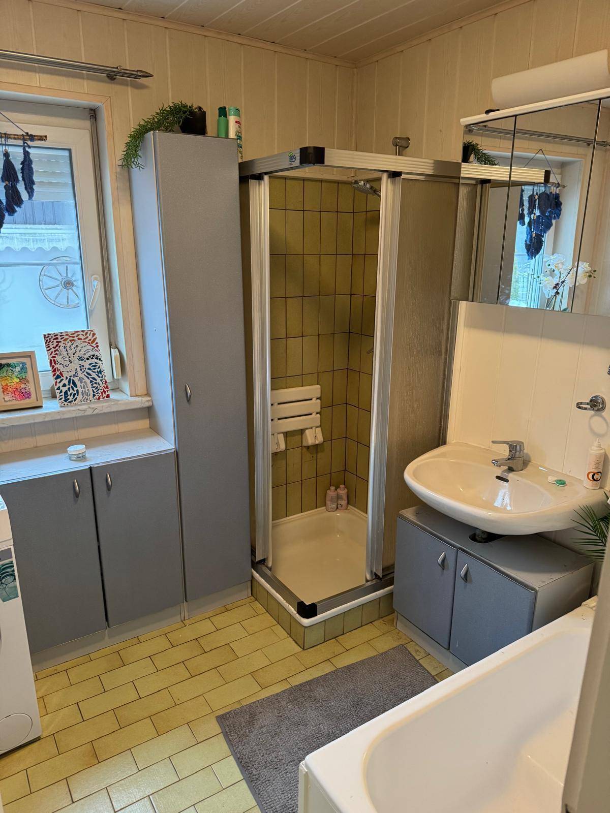 Badezimmer mit Duschkabine, Badewanne, Einzelwaschbecken und gelben Fliesen.