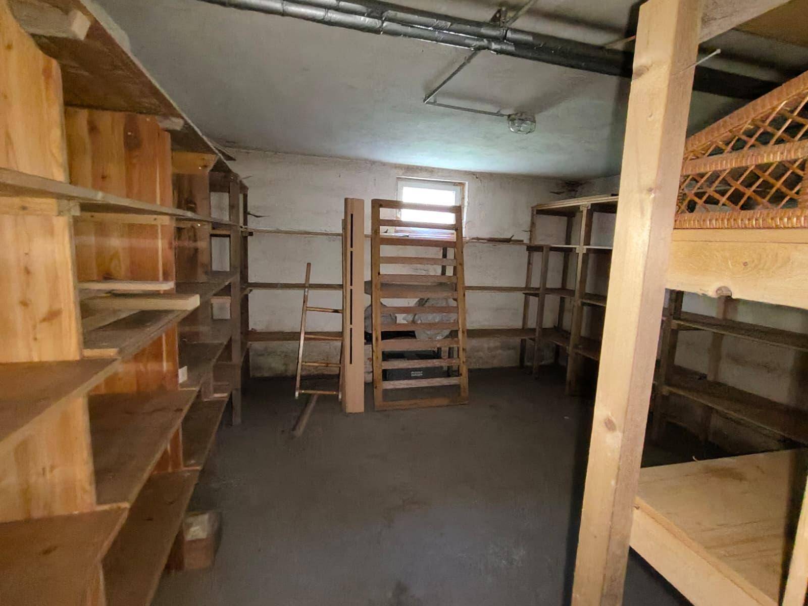 Geräumiger Kellerraum mit vielen Holzregalen und einem kleinen Fenster, ideal als Abstellraum.