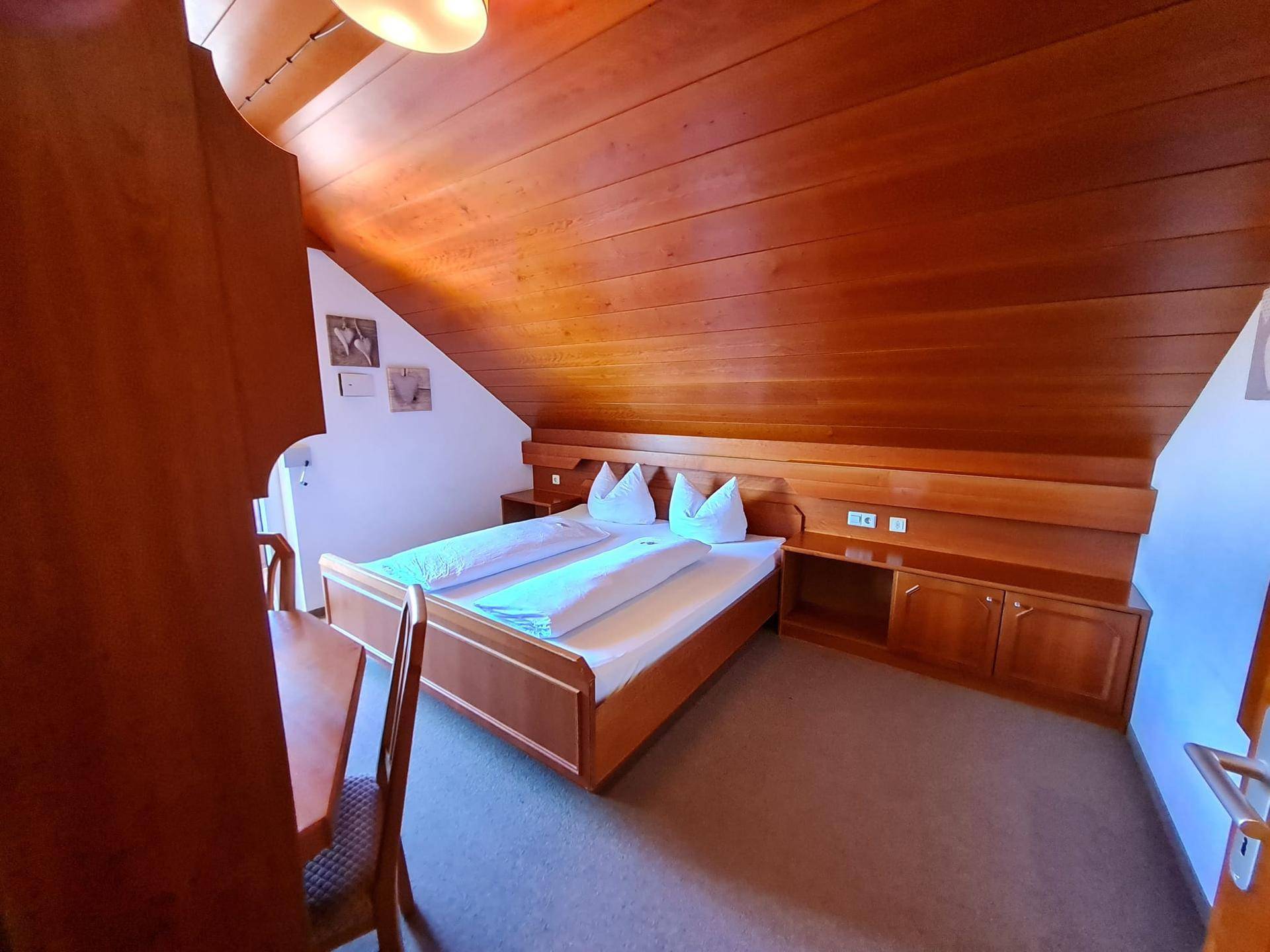 Gemütliches Schlafzimmer mit Doppelbett, Holzboden und Zugang zu einem Balkon.