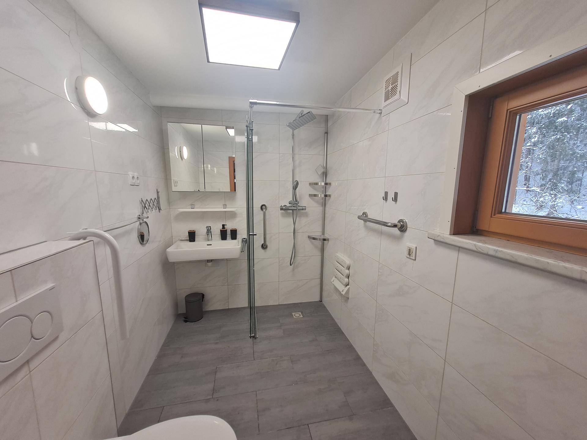 Modernes Badezimmer mit weißen Fliesen, barrierefreier Dusche, Einzelwaschbecken und Fenster.
