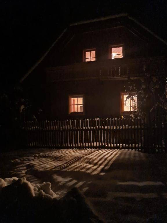 Verschneites Chalet in der Nacht mit beleuchteten Fenstern und winterlicher Atmosphäre.