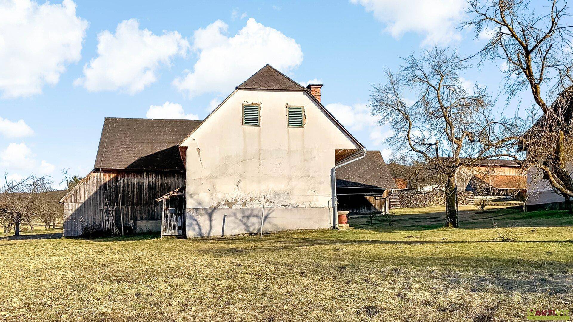 Rückansicht eines ländlichen Gebäudes mit einfacher Fassade und angrenzendem Feld.