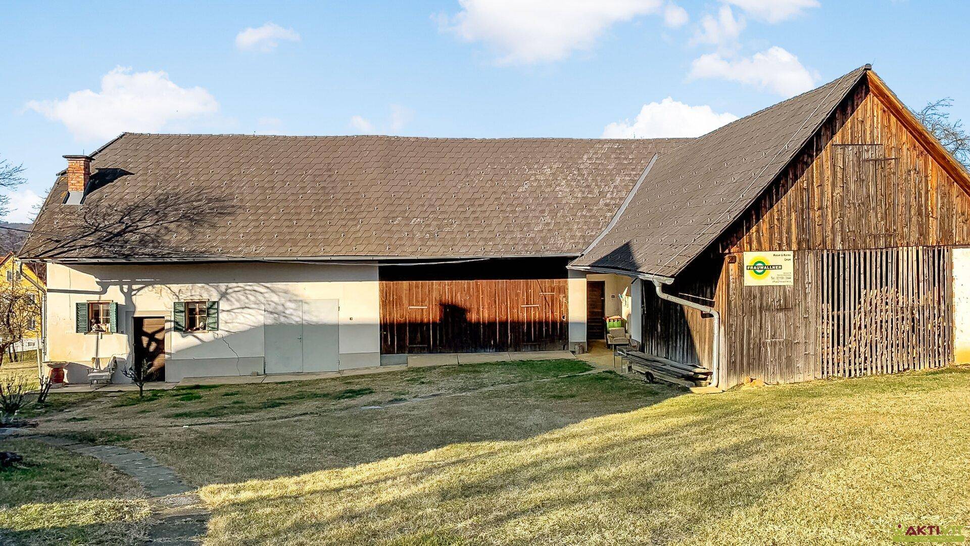 Ländliches Anwesen mit Scheune und Wohnhaus, umgeben von einer gepflegten Grünfläche.