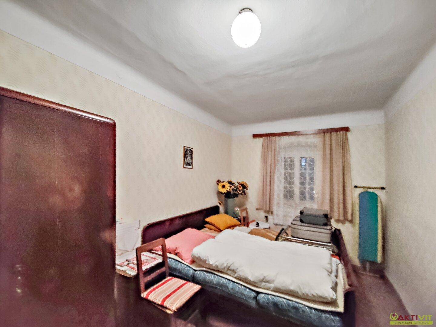 Kleines Schlafzimmer mit Einzelbett und einfacher Einrichtung.
