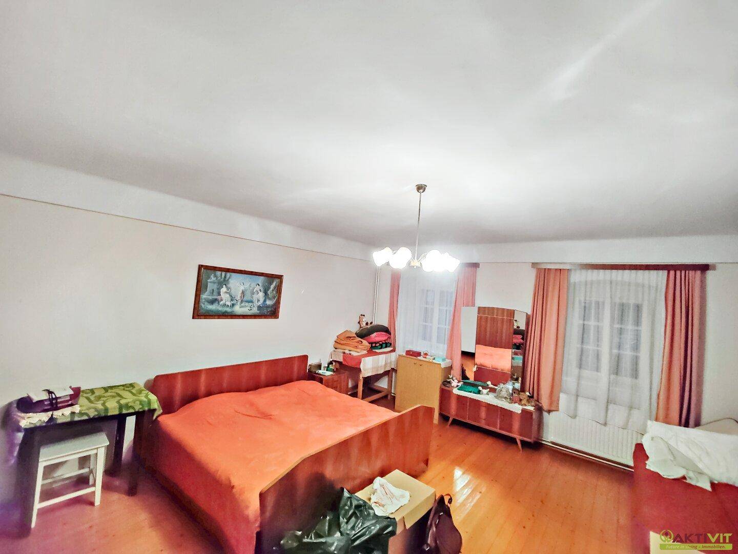 Schlafzimmer mit Doppelbett, Kommode und Fenster mit Blick nach draußen.