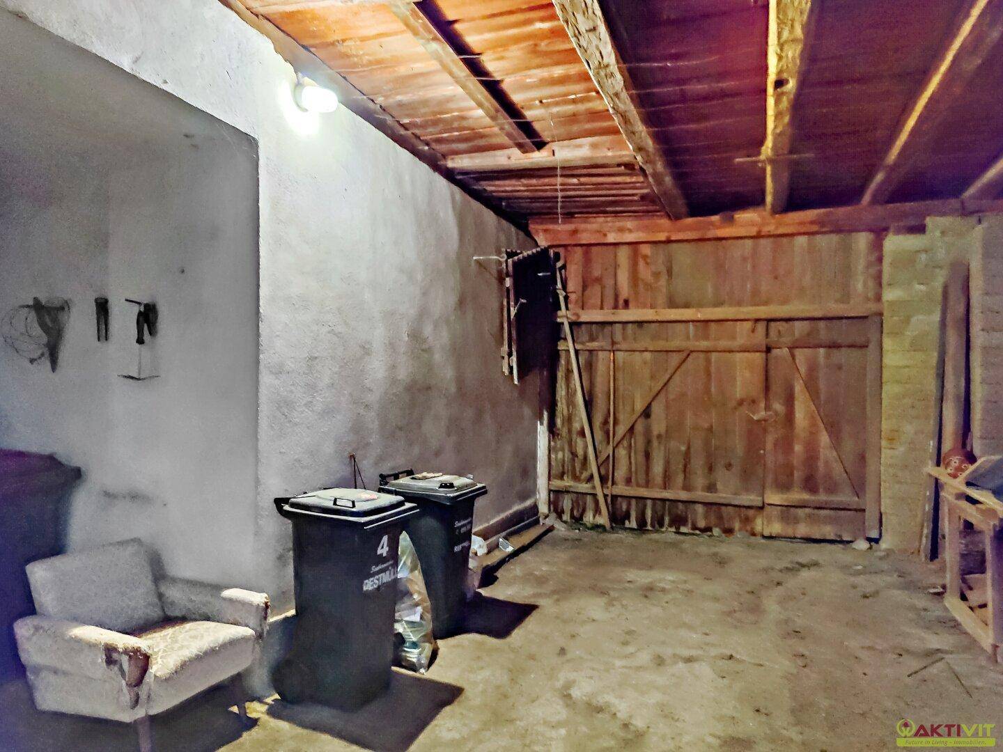 Geräumige Scheune mit Holztoren und Lagerflächen für verschiedene Gegenstände.