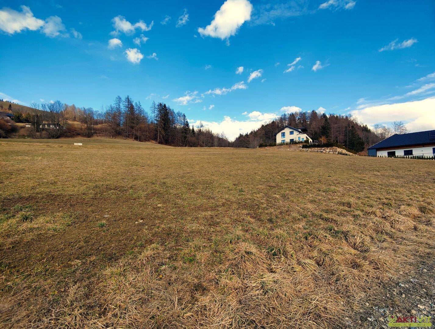 Großes Wiesengrundstück mit einem Haus im Hintergrund und bewaldeten Hügeln.