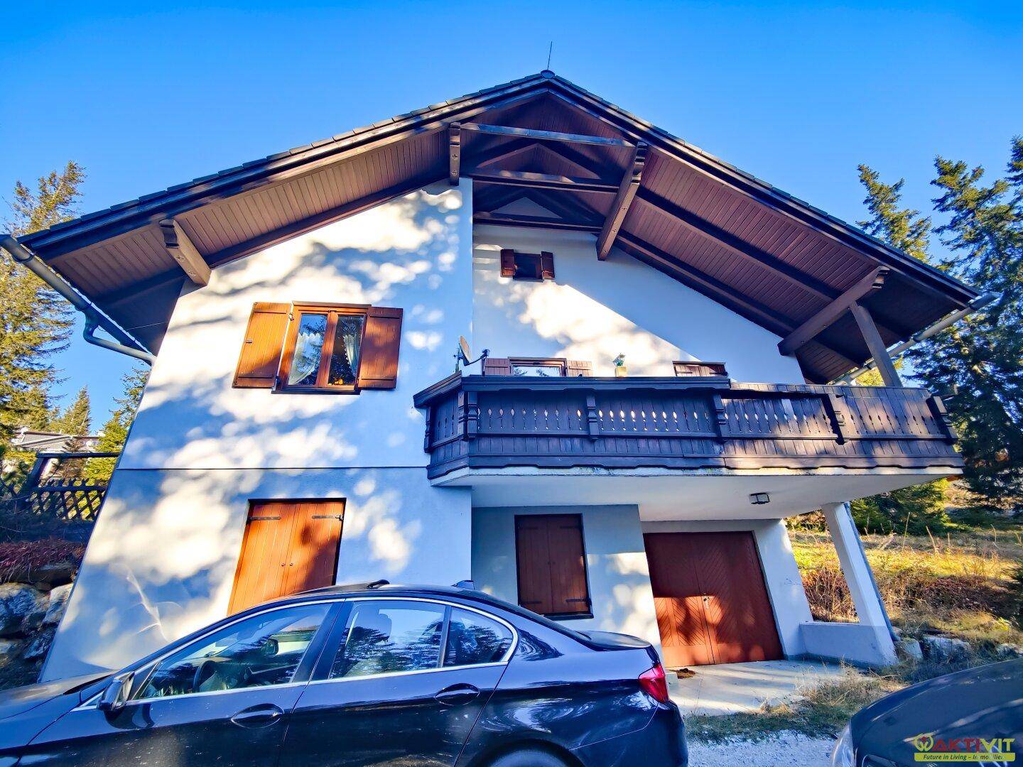 Charmantes Haus mit traditioneller Architektur und Holzbalkon, eingebettet in eine grüne Umgebung.