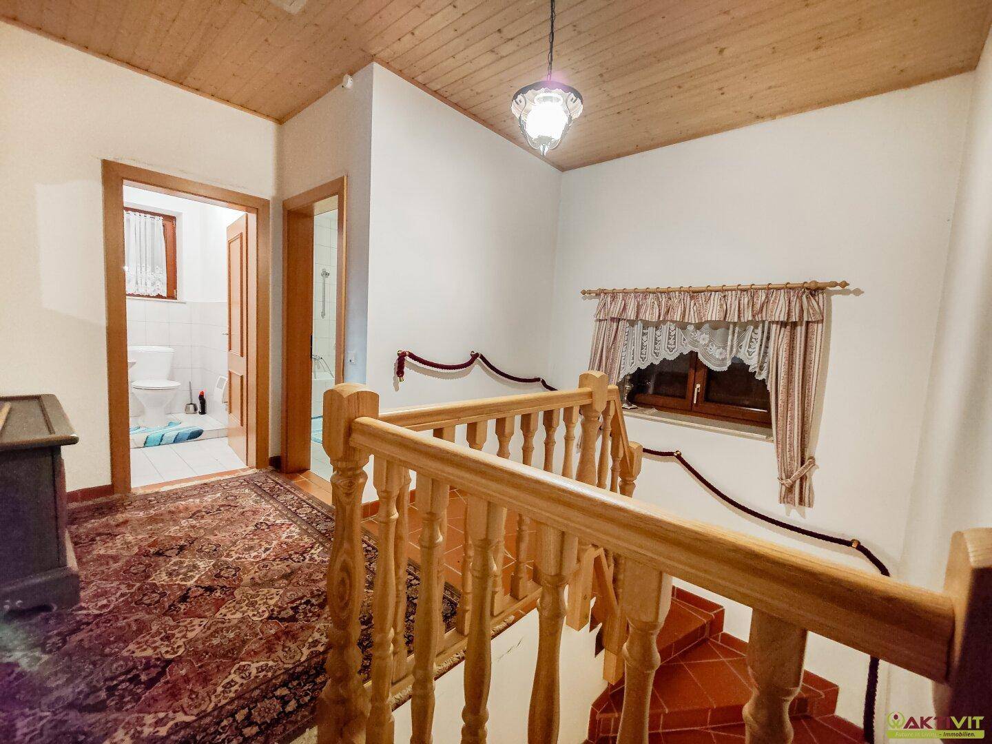 Heller Flur im Obergeschoss mit Holzdecke, Teppich und Zugang zu weiteren Räumen.