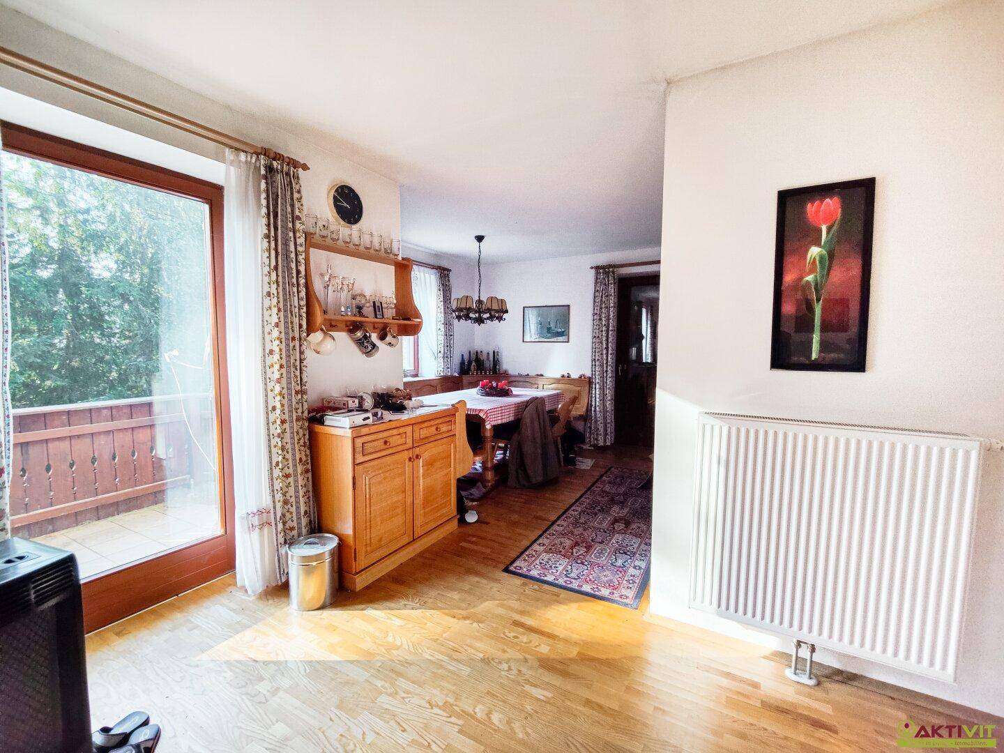 Essbereich mit Holzboden und großem Fenster, das viel Tageslicht hereinlässt.