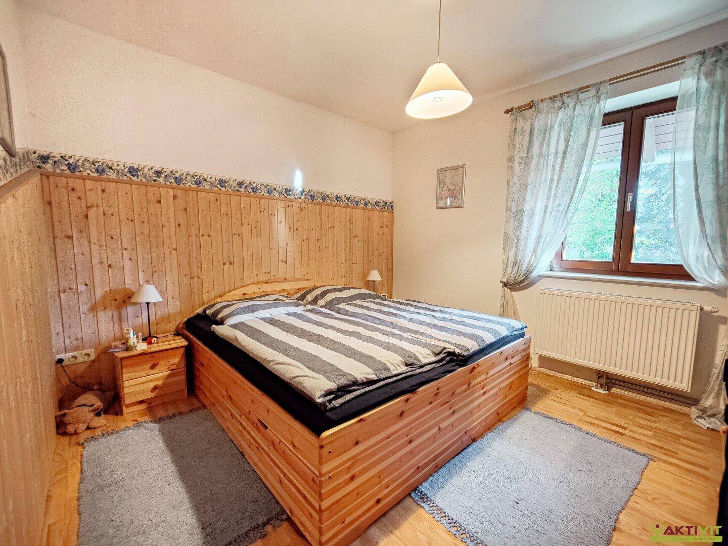 Gemütliches Schlafzimmer mit Holzvertäfelung, Doppelbett und Parkettboden.