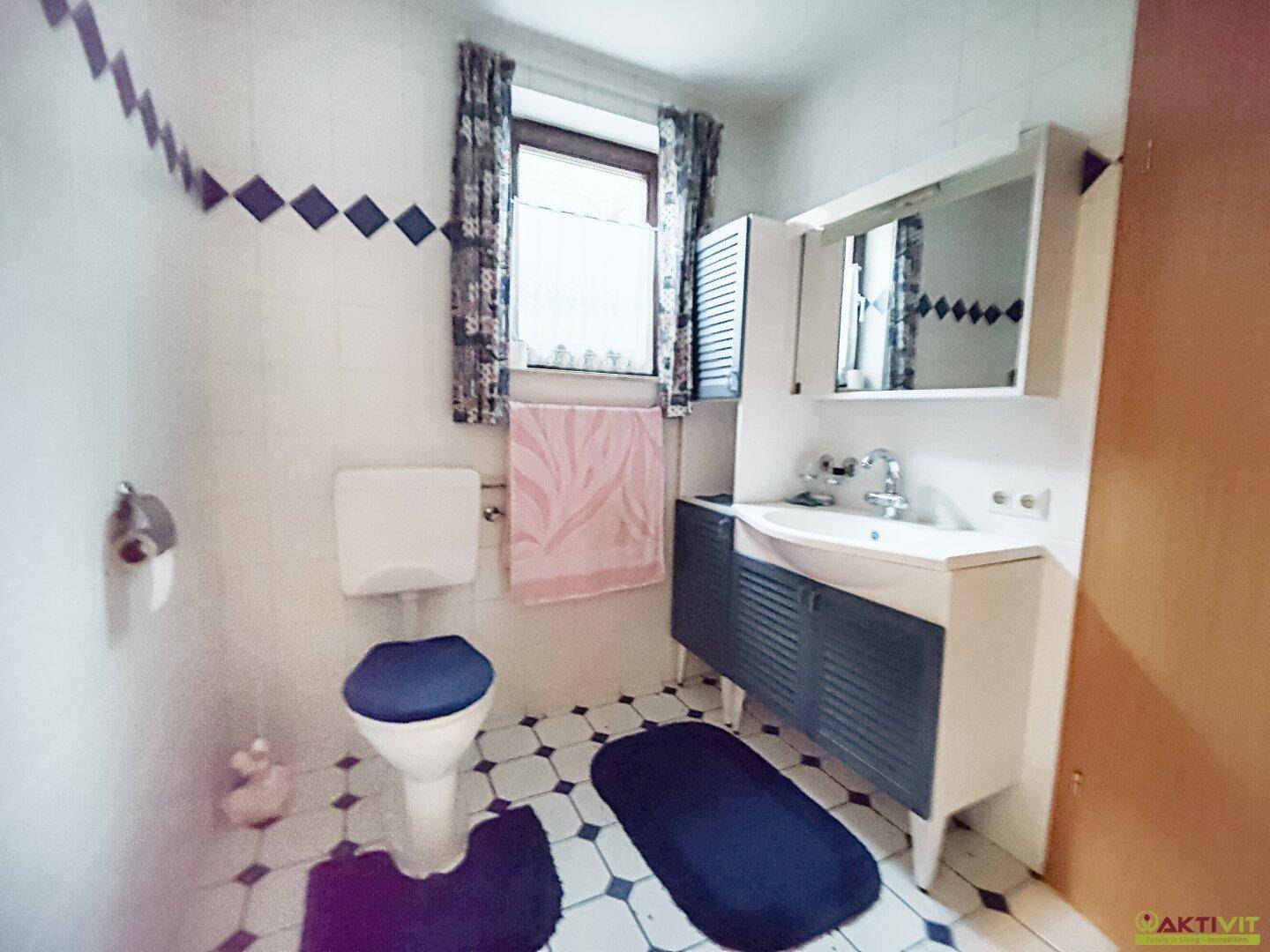 Badezimmer mit WC, Waschbecken und Duschkabine, gefliest in Weiß und Blau.
