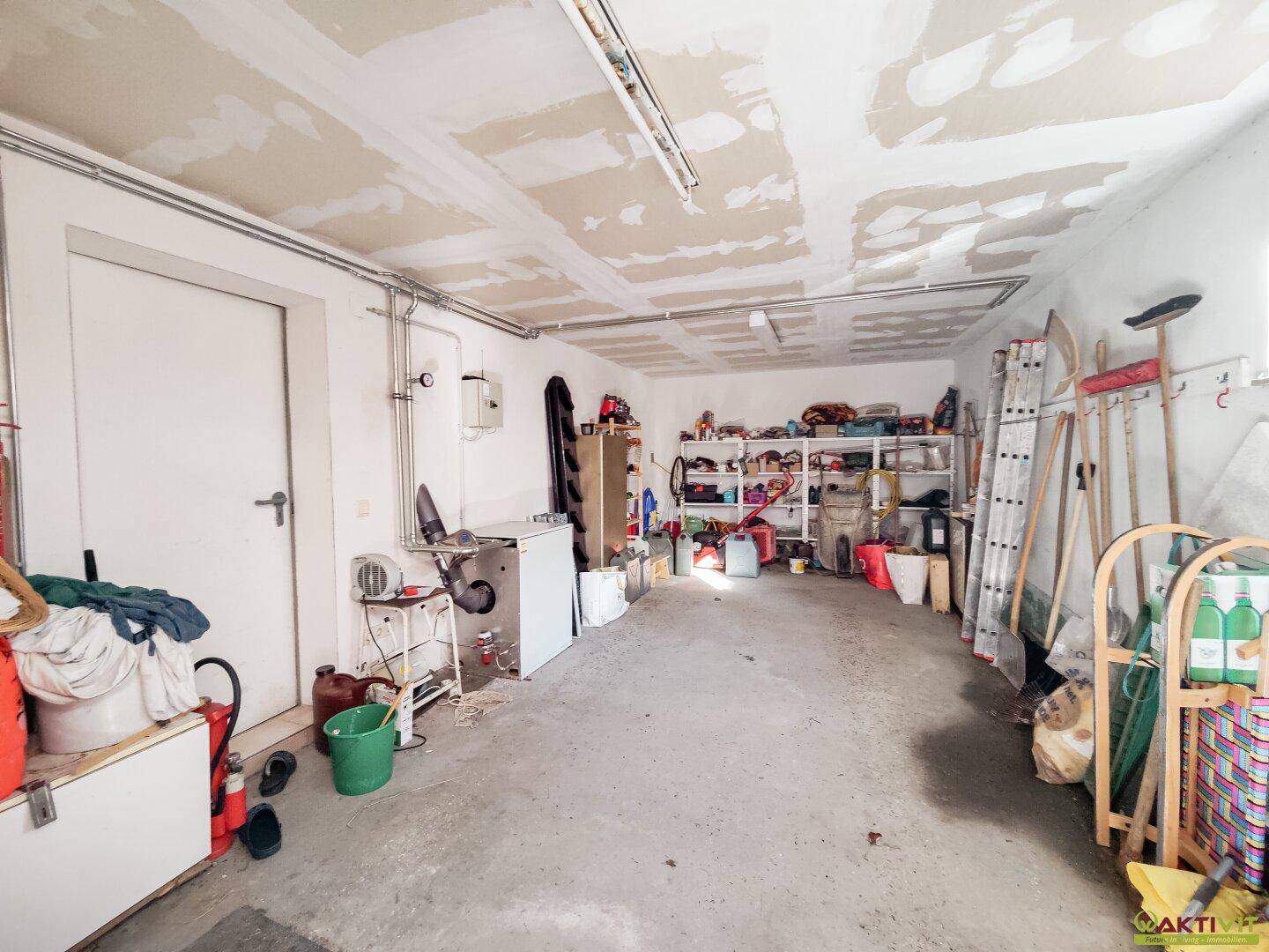 Geräumige Garage mit Betonboden und viel Stauraum für Werkzeuge und Haushaltsgegenstände.