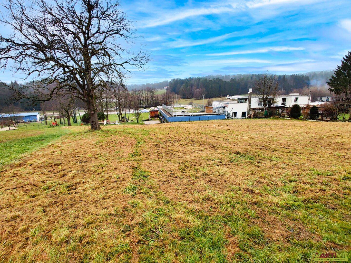 Großes Grundstück mit Blick auf umliegende Gebäude und eine Freizeitanlage in der Ferne.