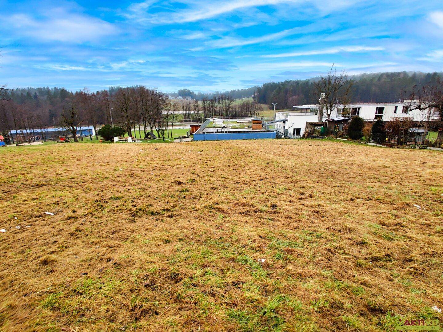 Weitläufiges Gelände mit Blick auf eine Sportanlage und weitere Gebäude unter bewölktem Himmel.
