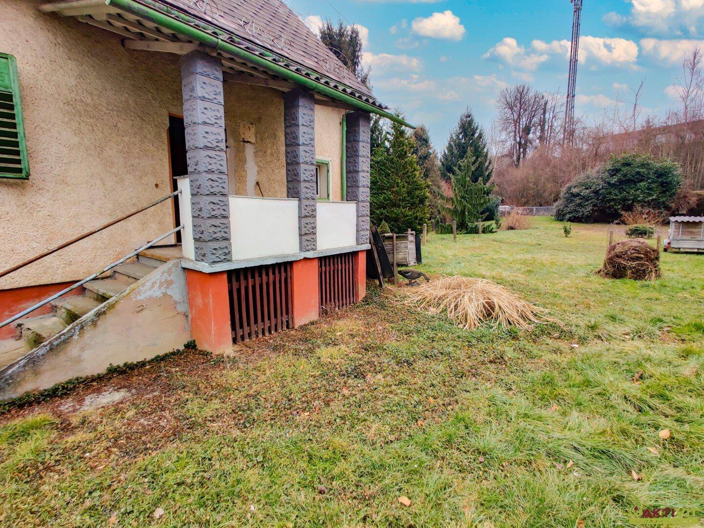 Überdachter Eingangsbereich des Hauses mit Säulen und Blick auf die weitläufige Rasenfläche.