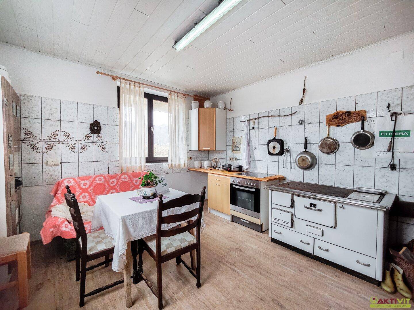 Rustikale Wohnküche mit traditionellem Holzofen, Essbereich und Fenster.