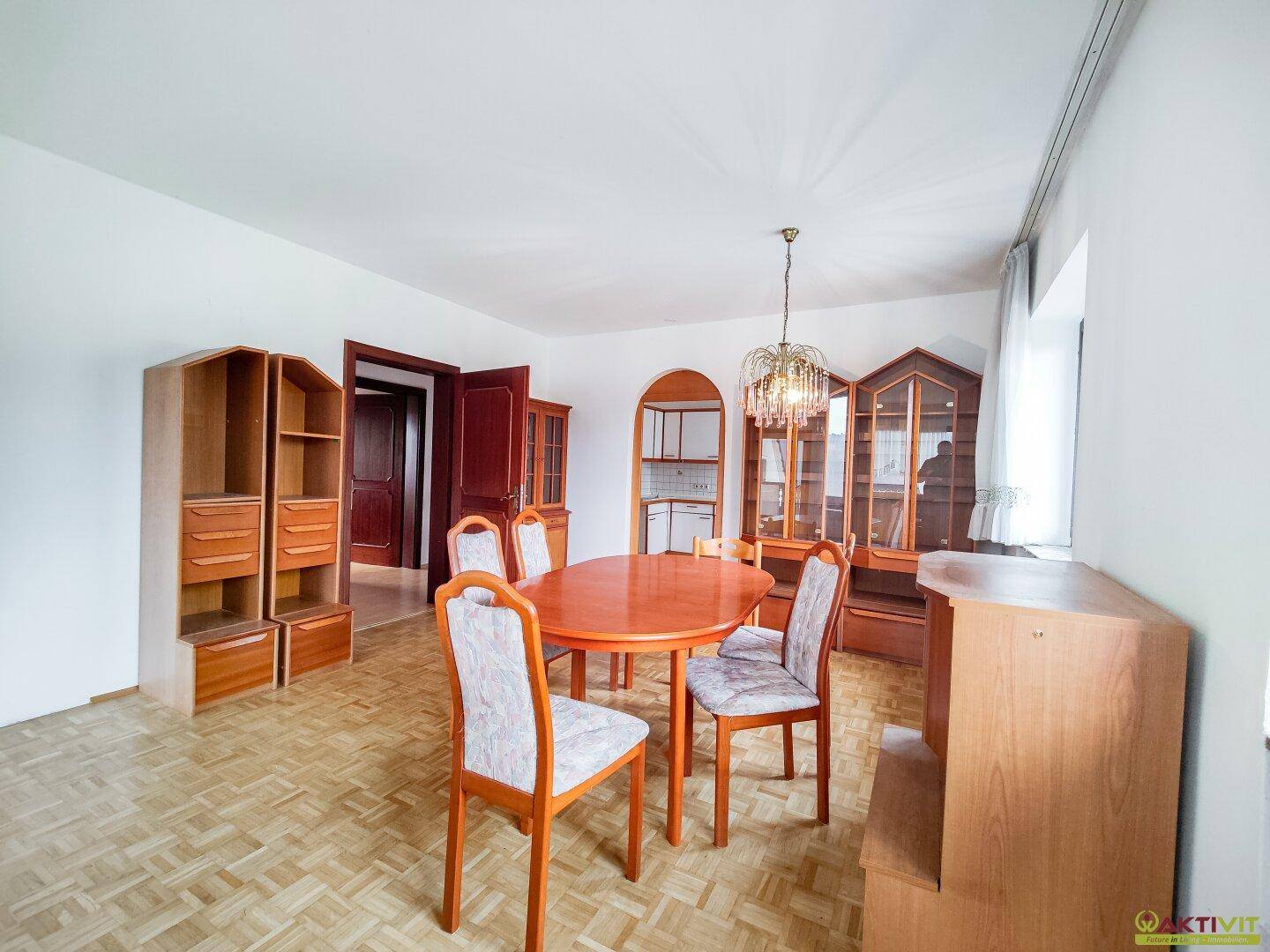 Esszimmer mit Parkettboden, Esstisch und traditionellen Holzschränken.