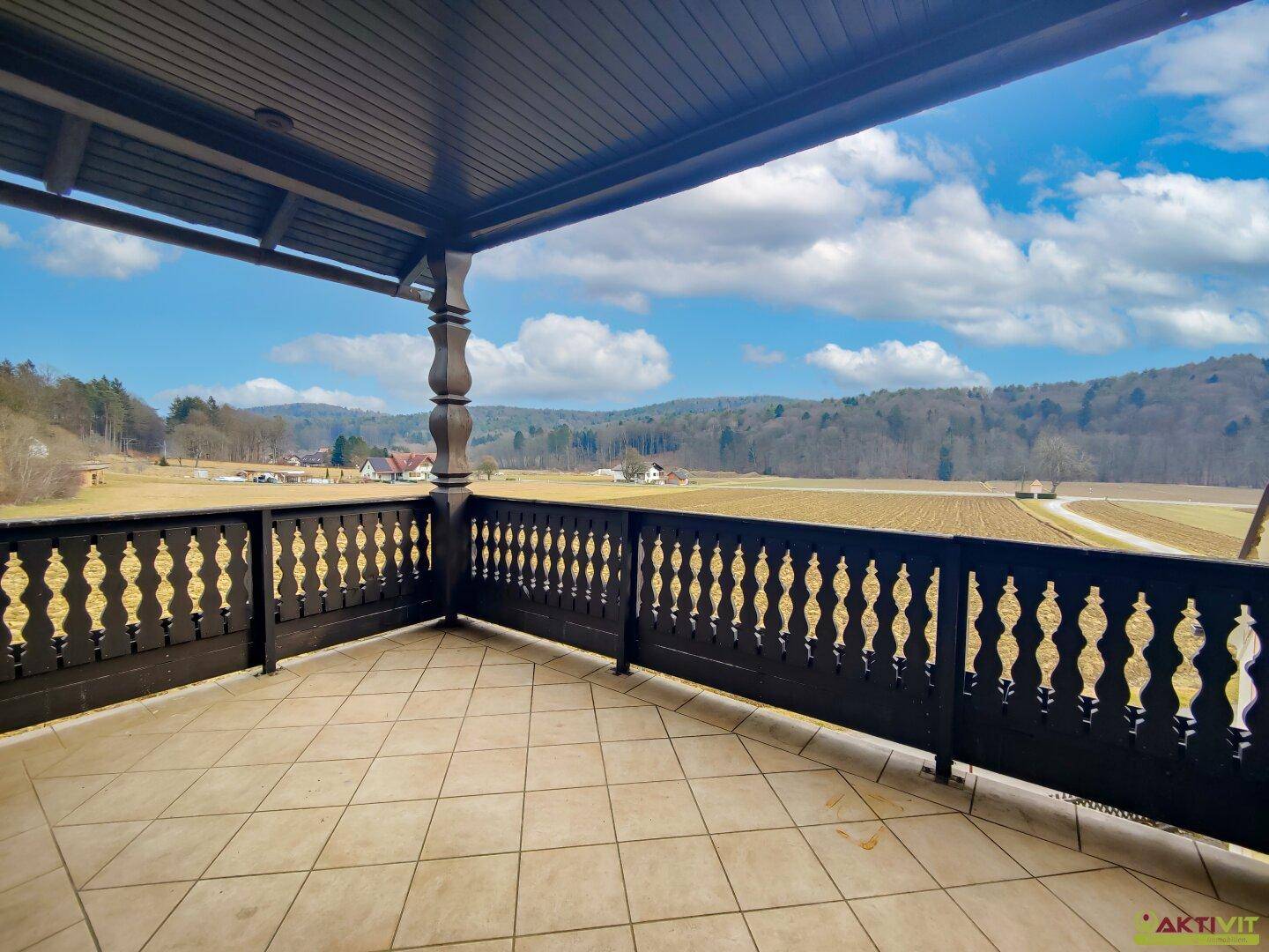 Überdachter Balkon mit traditionellem Geländer und weitem Blick über die Landschaft.