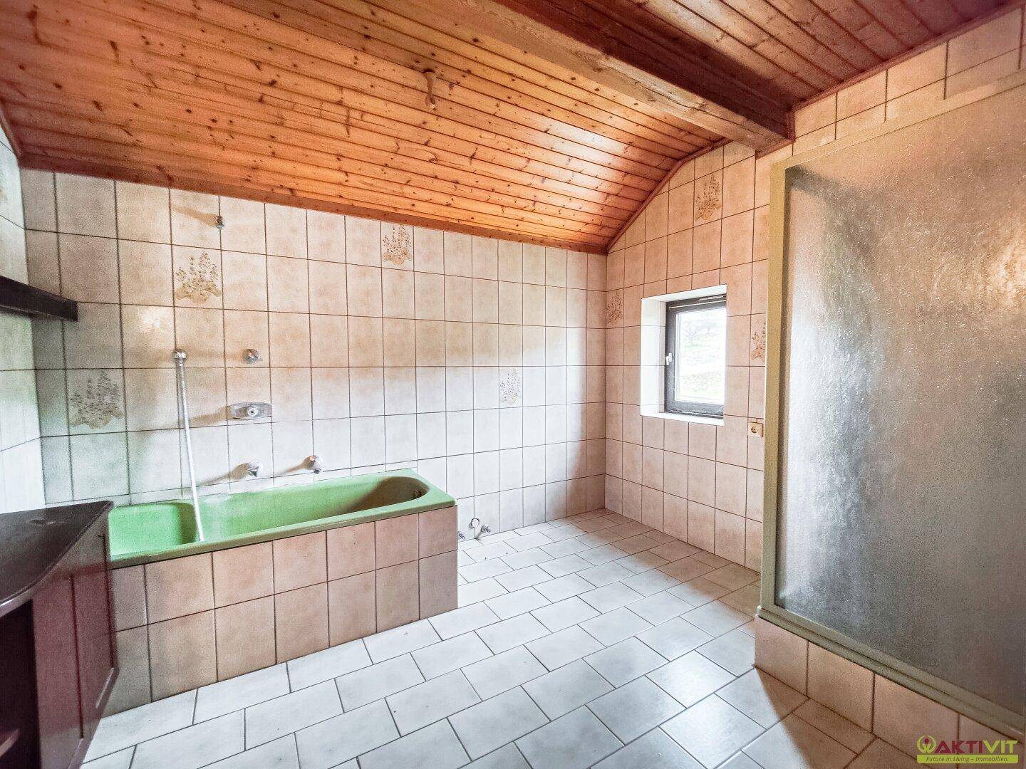 Badezimmer mit grüner Badewanne, Dusche und beigefarbenen Fliesen.