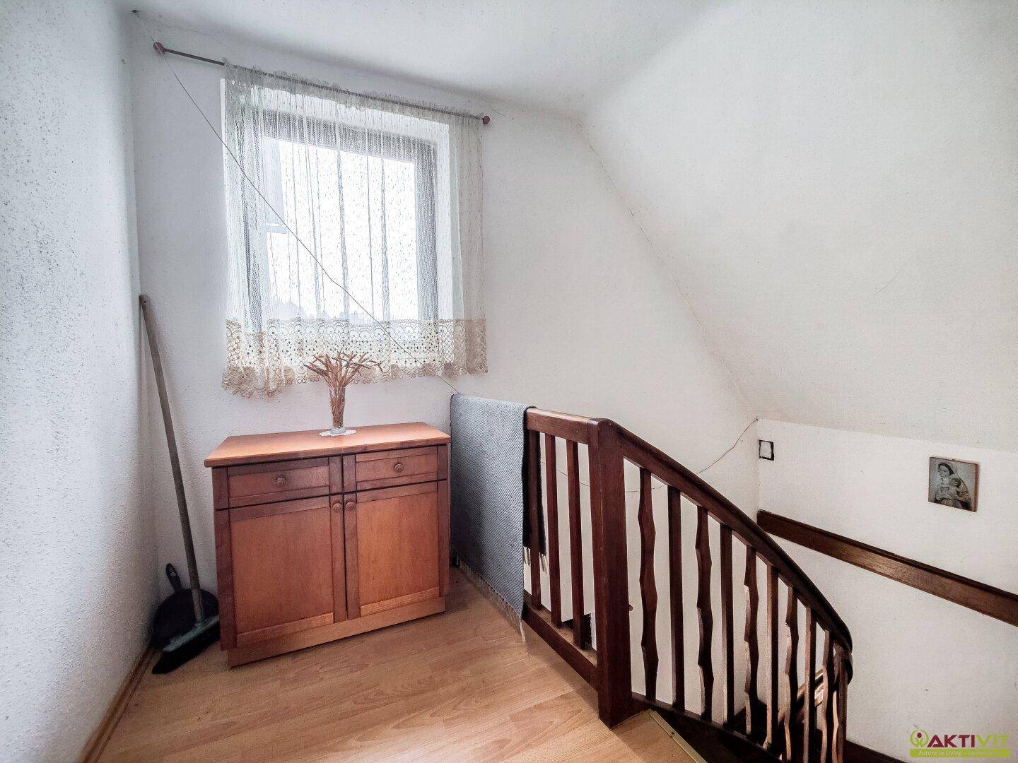 Dachgeschossflur mit schräger Decke und Holztreppe.