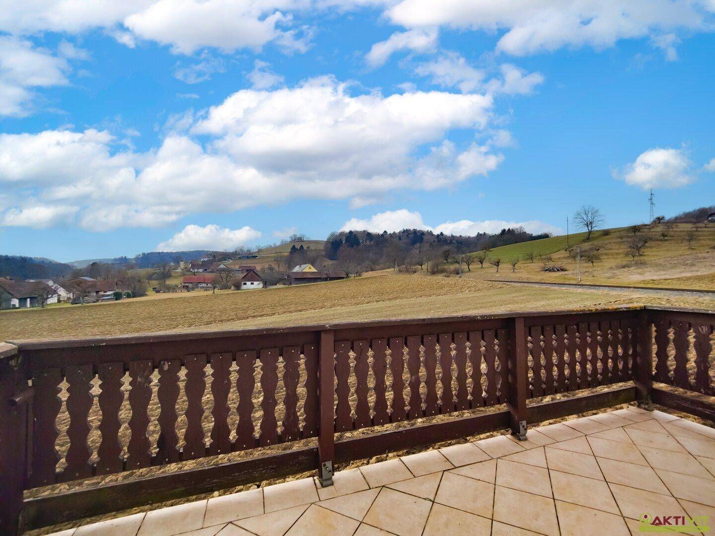 Balkon mit traditionellem Holzgeländer und weitem Blick über die ländliche Umgebung.