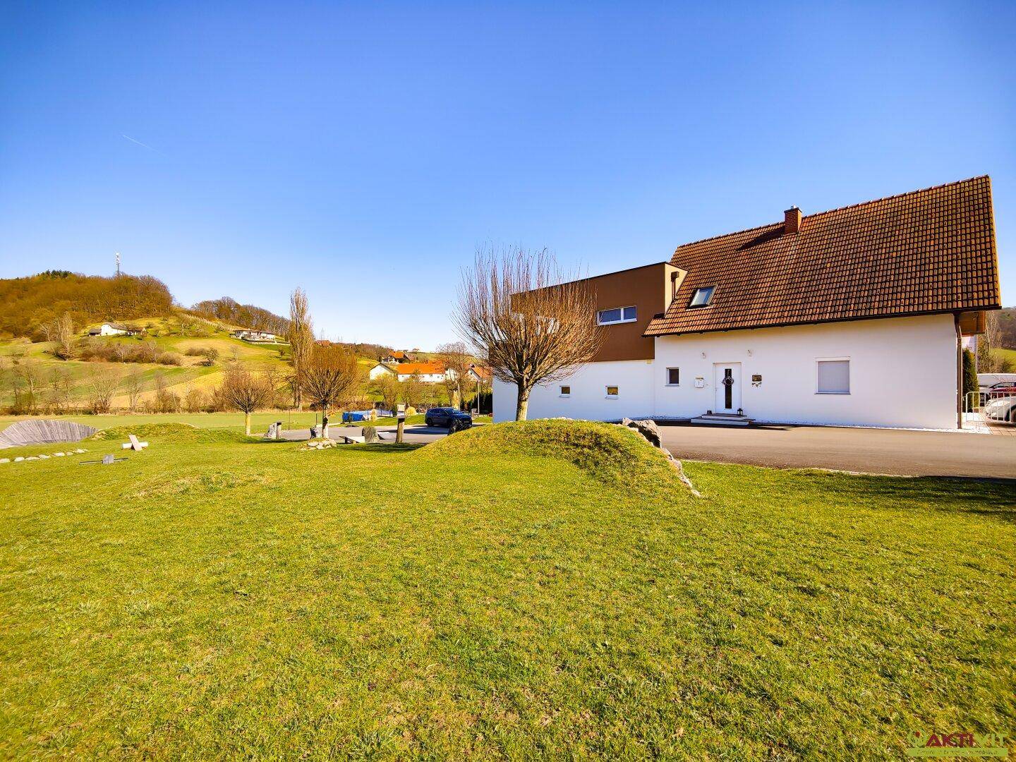 Weitläufige Außenansicht des modernen Hauses mit gepflegtem Rasen und ländlicher Umgebung.