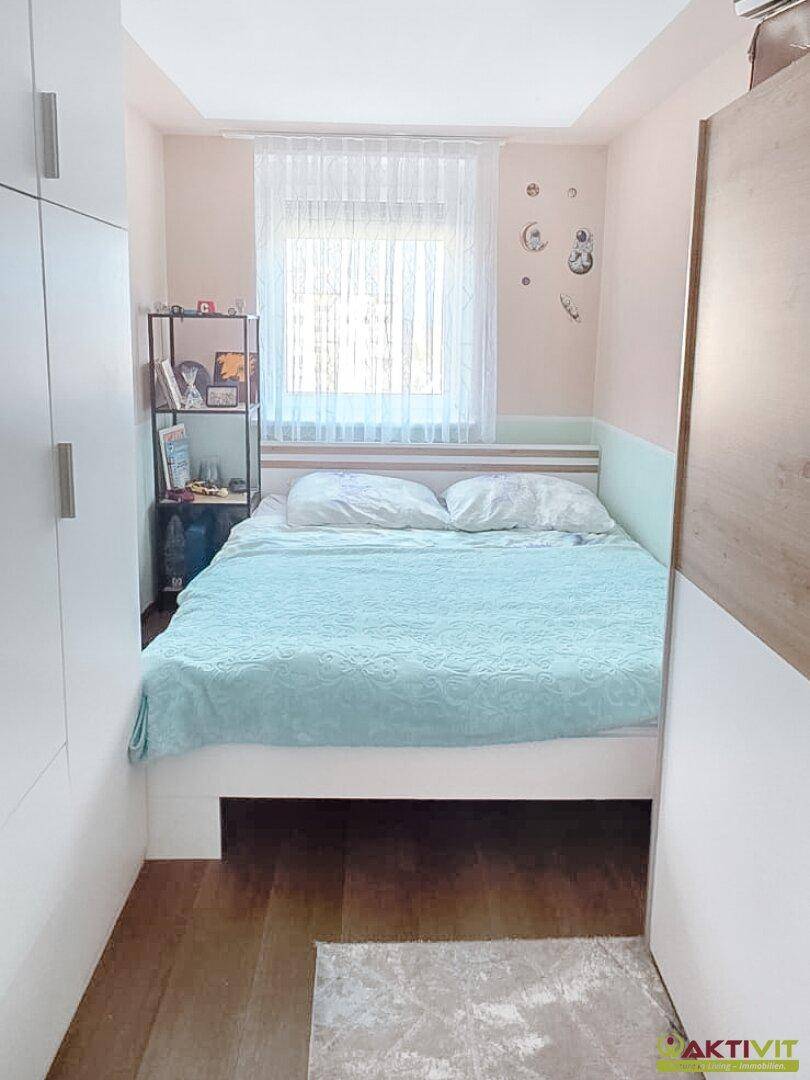 Gemütliches Schlafzimmer mit Doppelbett, Holzboden und weißem, raumhohem Kleiderschrank.