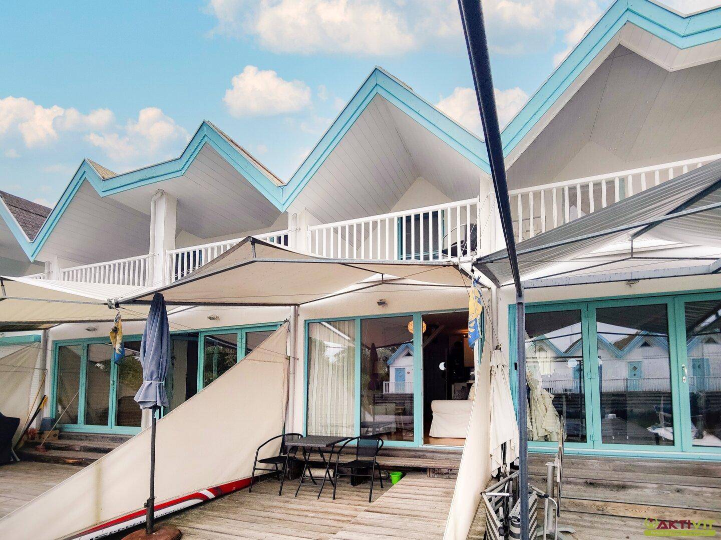 Eine einladende Terrasse mit Sitzgelegenheiten vor der modernen Fassade der Ferienhäuser.