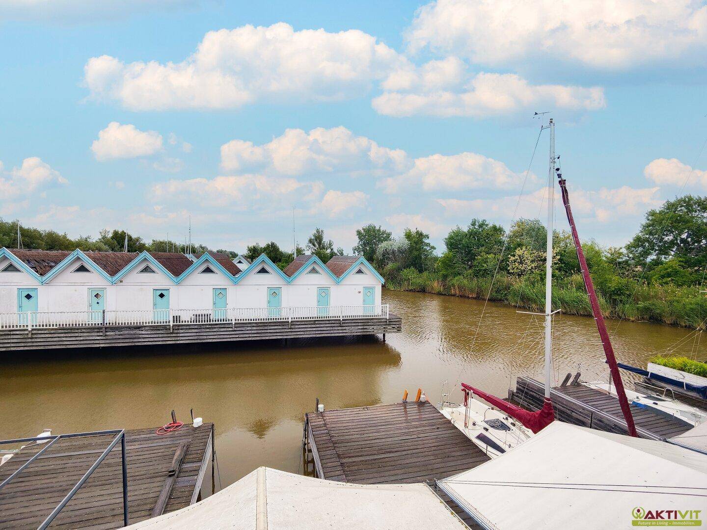 Panoramablick auf die Ferienhäuser am Wasser mit Booten und üppiger Vegetation.
