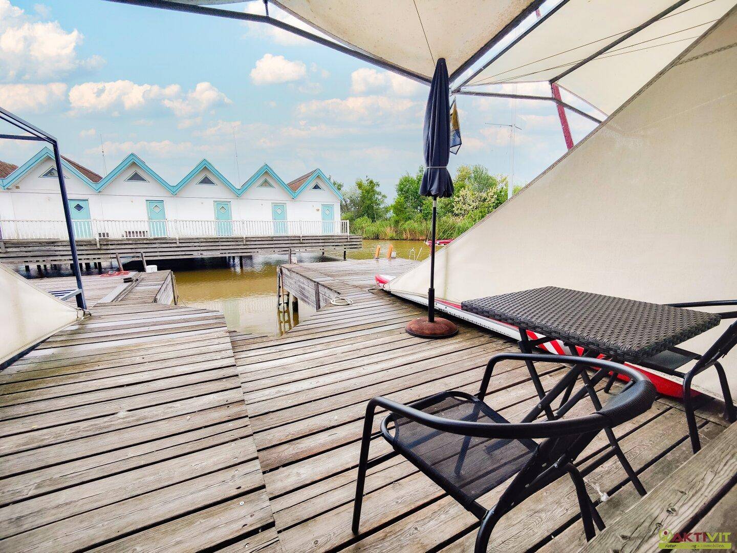Geräumige Holzterrasse mit Sitzgelegenheiten und Blick auf die Wasserhäuser.