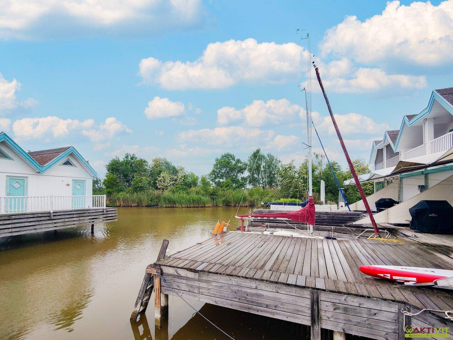 Blick auf den Kanal mit Bootsanlegestellen und den charmanten Ferienhäusern im Hintergrund.