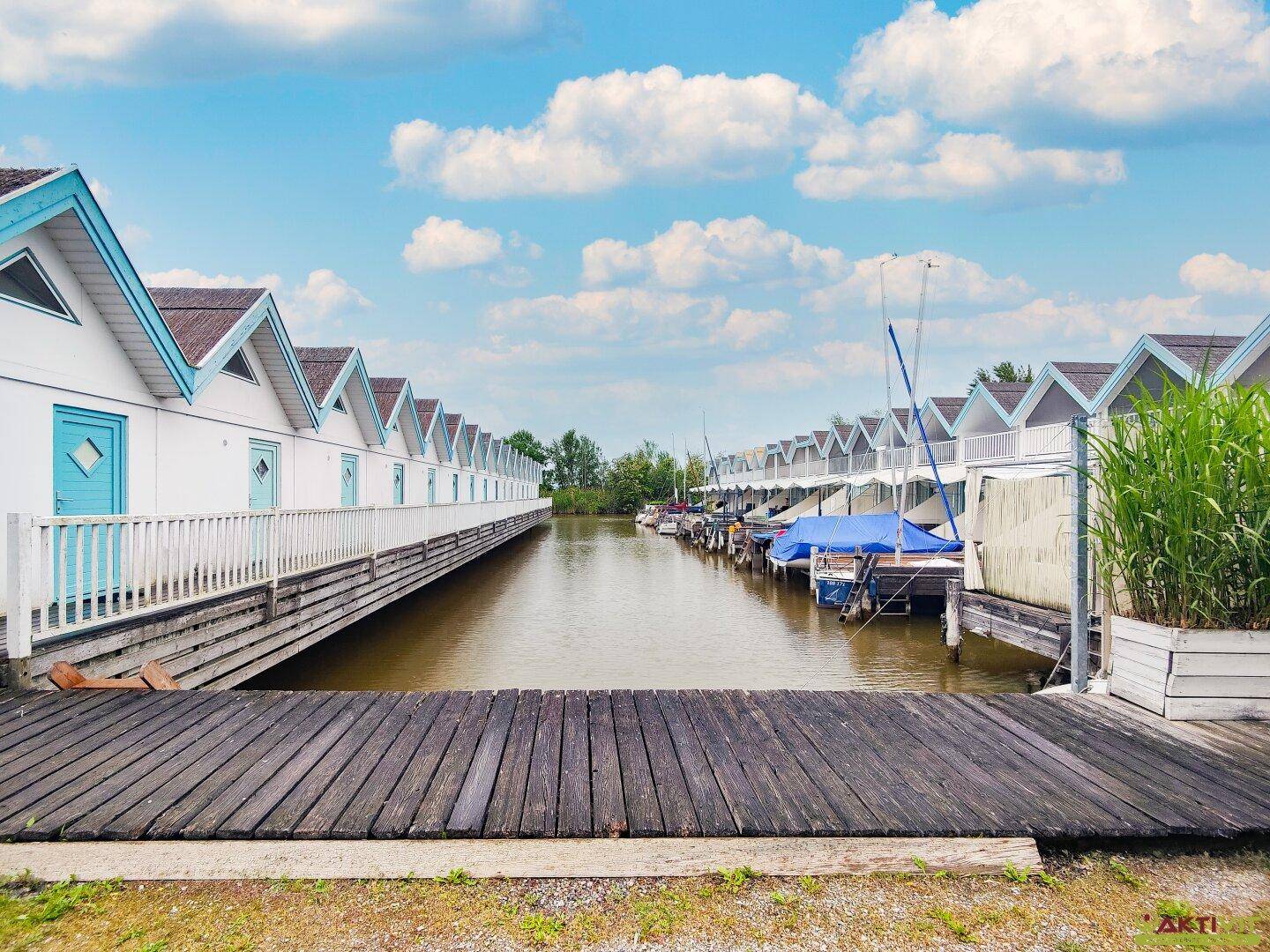 Blick entlang des Kanals mit Ferienhäusern auf beiden Seiten und Bootsanlegestellen.