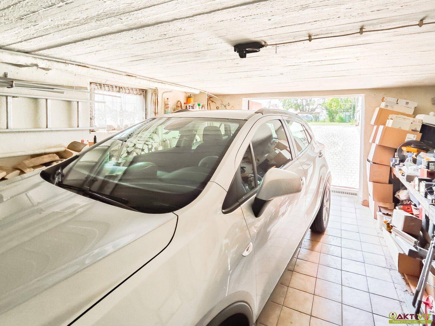 Geräumige Garage mit Fliesenboden und Platz für ein Fahrzeug, bietet sicheren Unterstand.
