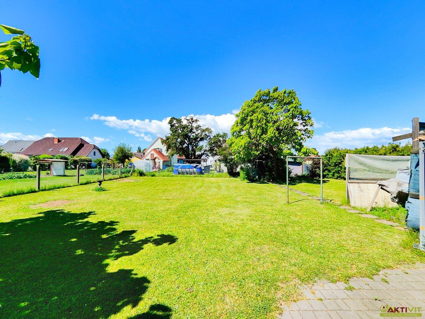 Weitläufige Rasenfläche im Garten mit Blick auf die umliegenden Häuser und viel Grün.