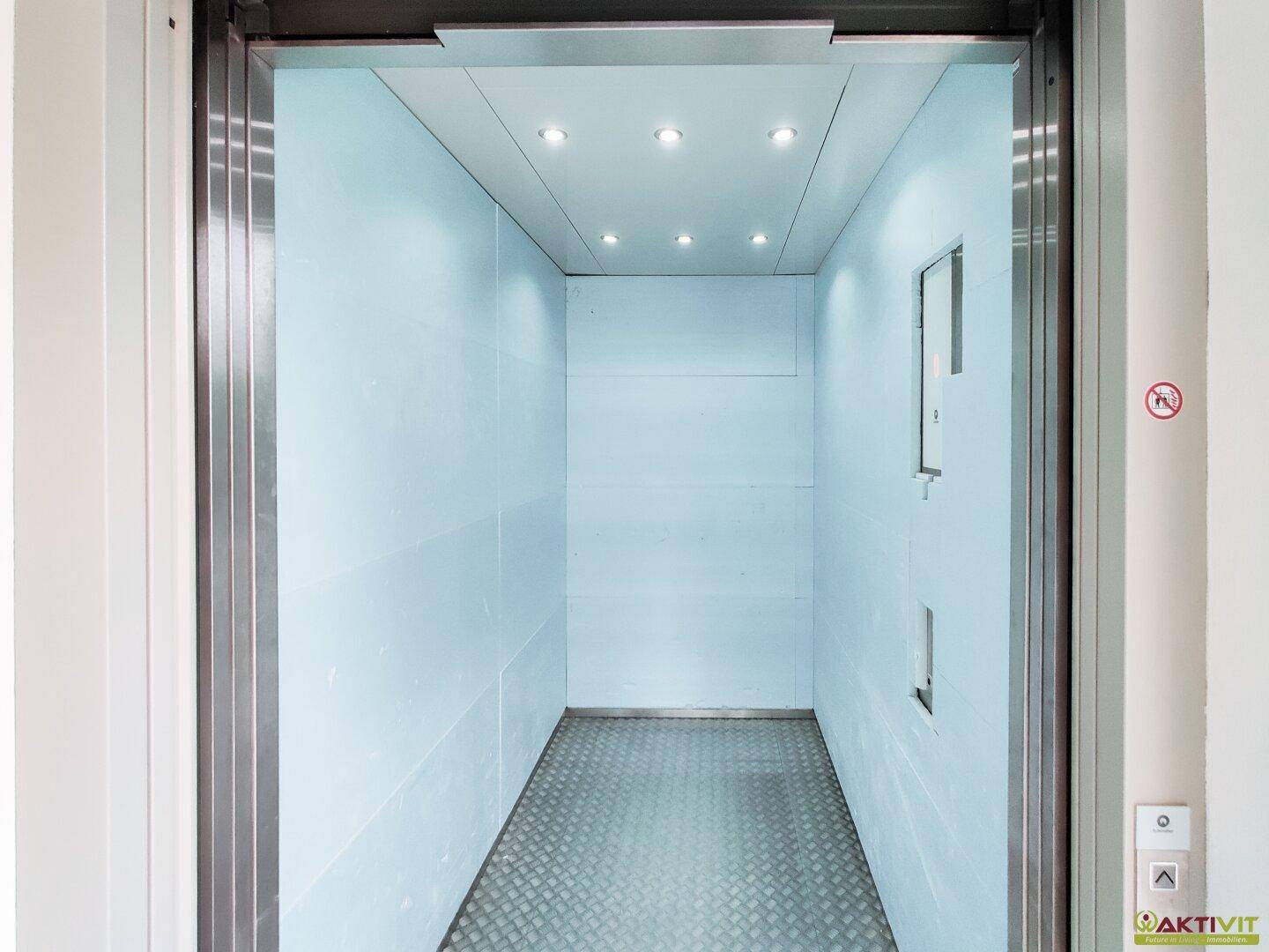 Moderner Aufzug mit Edelstahlwänden und geprägtem Boden, ausgestattet mit Deckenleuchten.