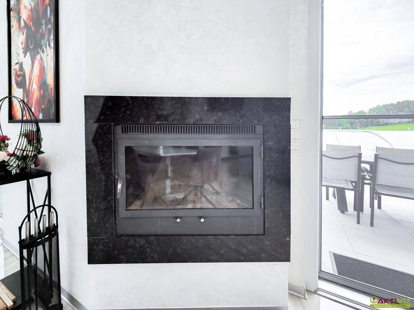 Moderner Kamin mit schwarzer Granitverkleidung, integriert in den Wohnbereich.