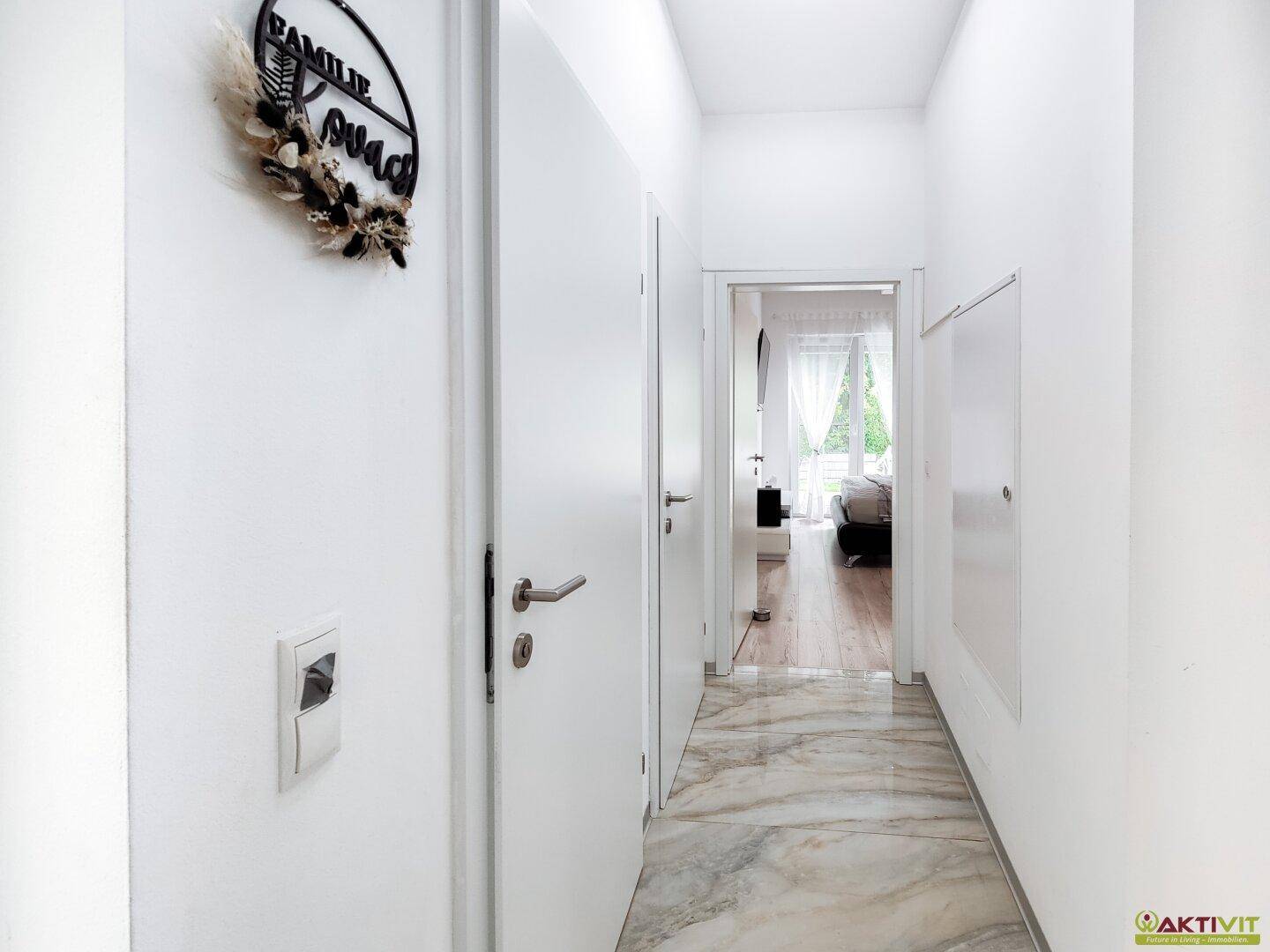 Heller Flur mit Marmorboden, weißen Türen und Blick in ein Schlafzimmer.