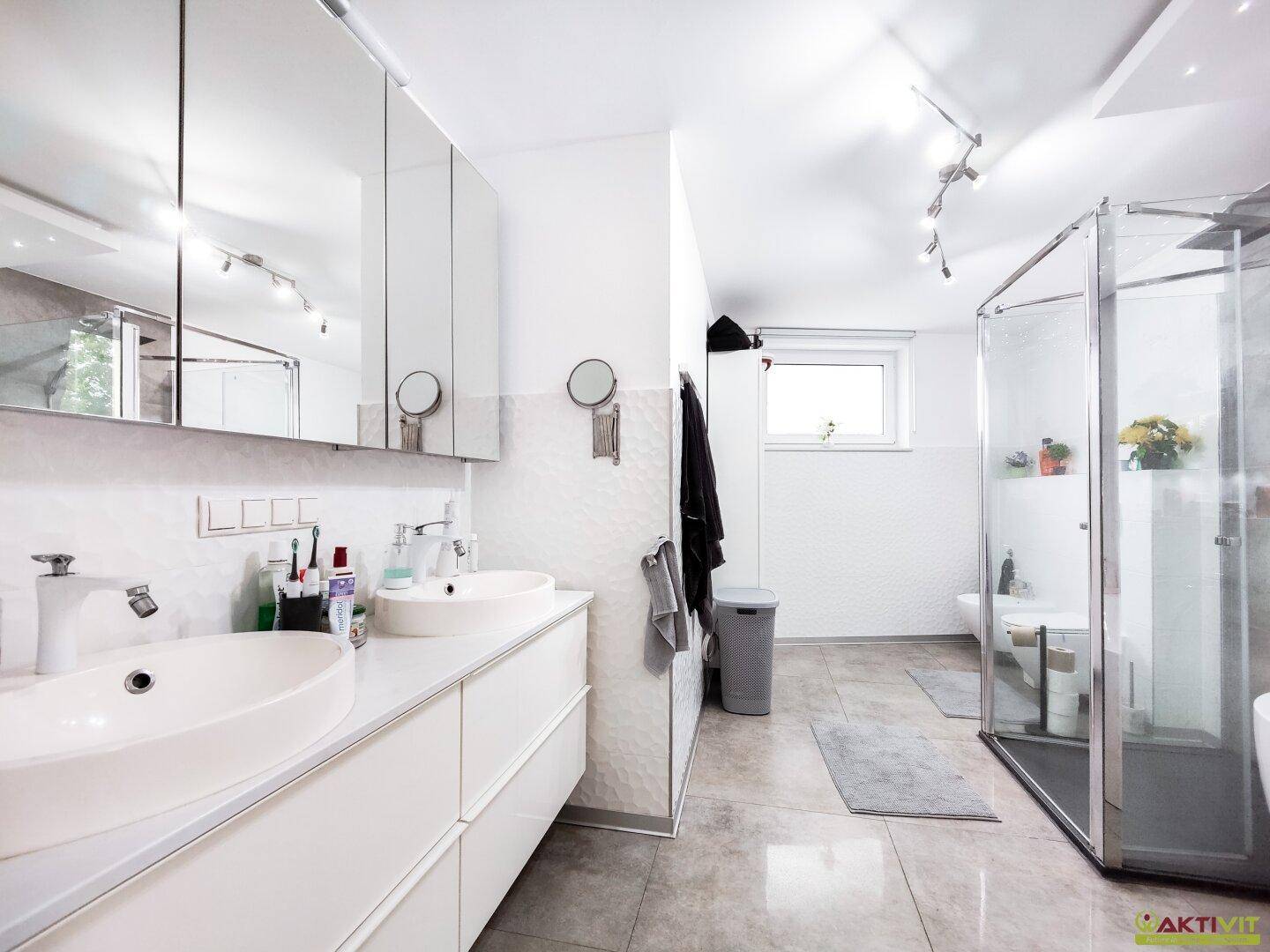 Modernes Badezimmer mit Doppelwaschbecken, Spiegelschrank und Duschkabine.
