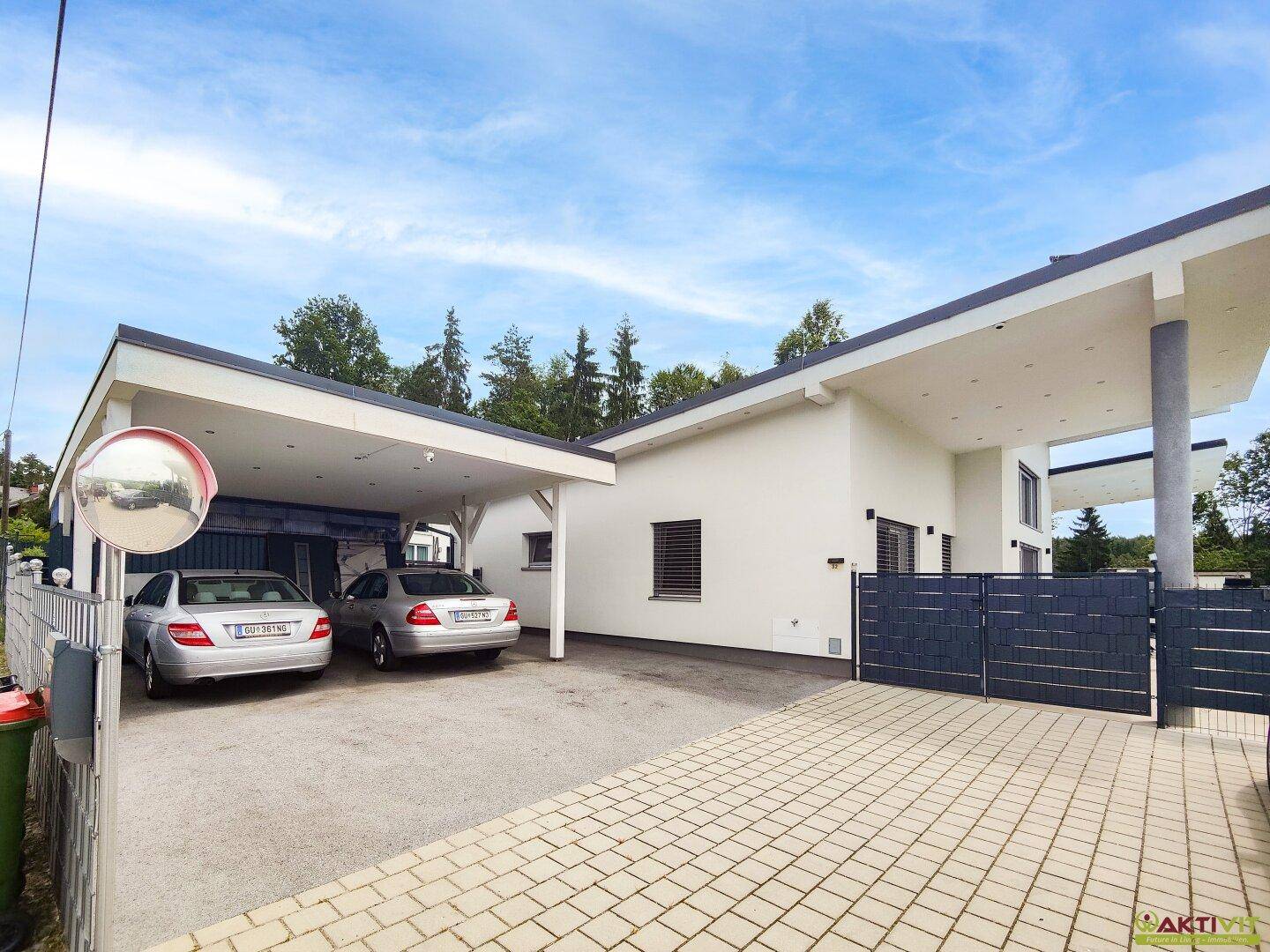 Moderne Architektur mit Doppelcarport und gepflasterter Einfahrt vor dem Haus.