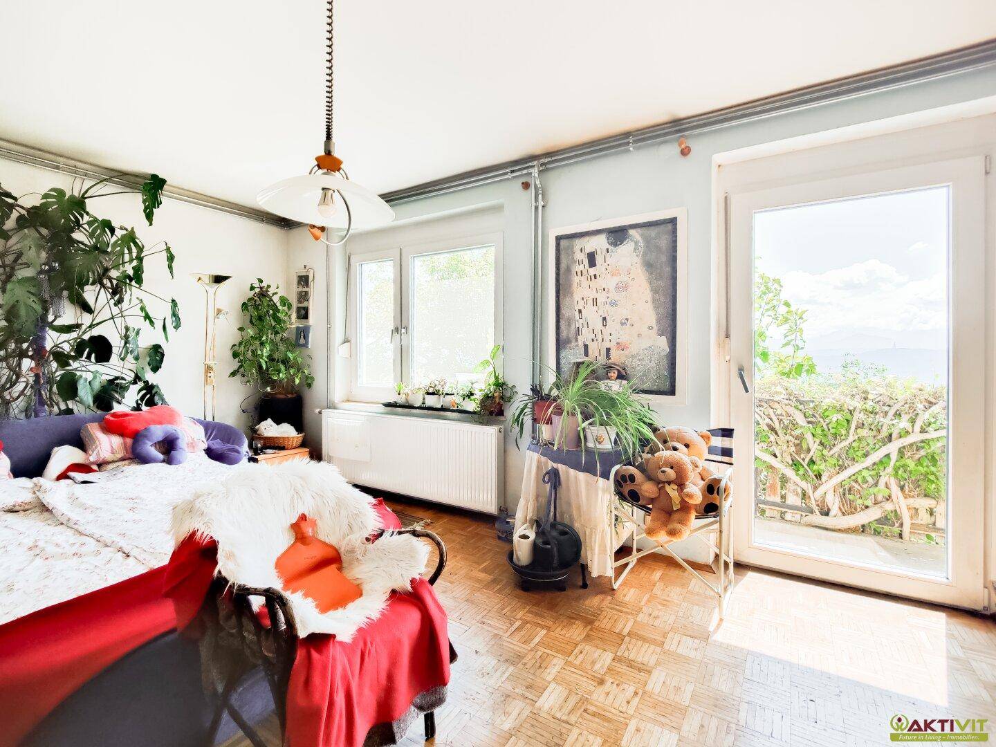 Helles Wohnzimmer mit Parkettboden, vielen Pflanzen und Zugang zu einem Balkon mit Weitblick.