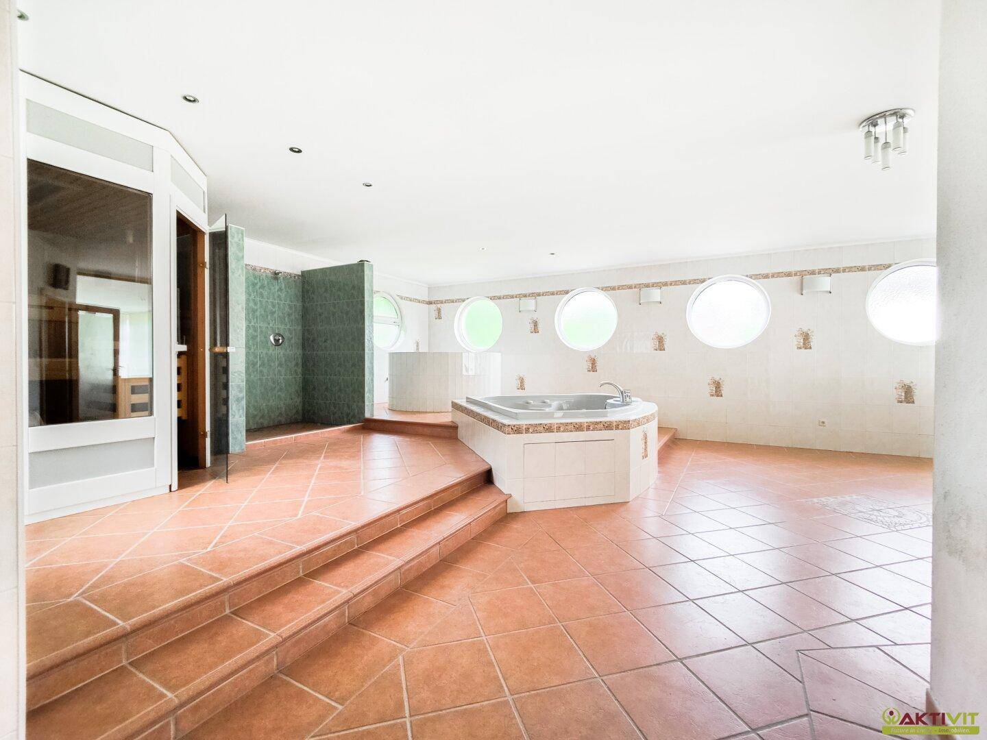 Großer Wellnessbereich mit Whirlpool, Sauna und runden Fenstern, ideal zur Entspannung.