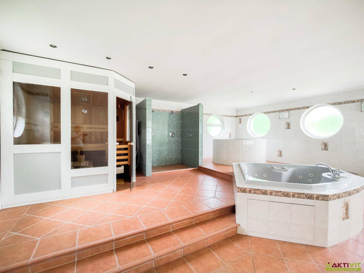 Geräumiger Wellnessbereich mit Whirlpool, Sauna und Dusche, ausgestattet mit Terrakottafliesen.