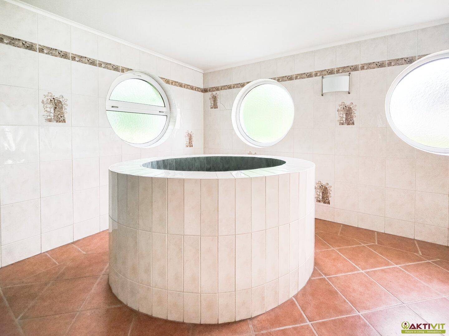 Runder Pool oder Tauchbecken im Wellnessbereich, umgeben von hellen Fliesen und runden Fenstern.