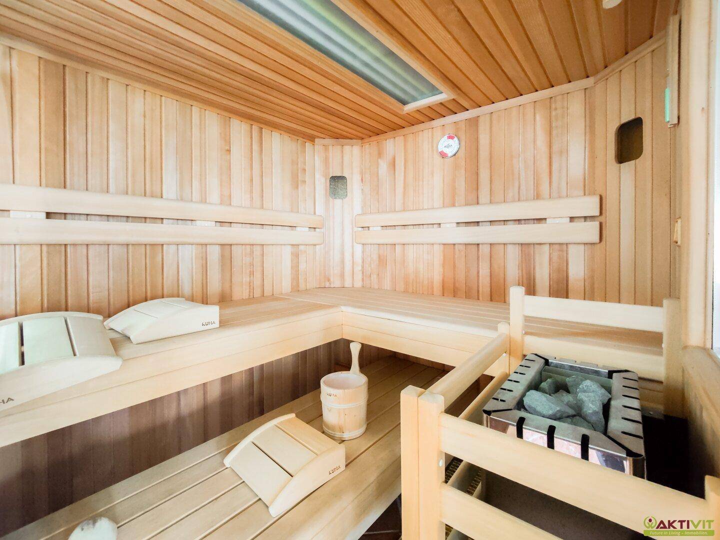 Innenansicht der Holzsauna mit Bänken und Saunaofen, bereit für entspannende Stunden.