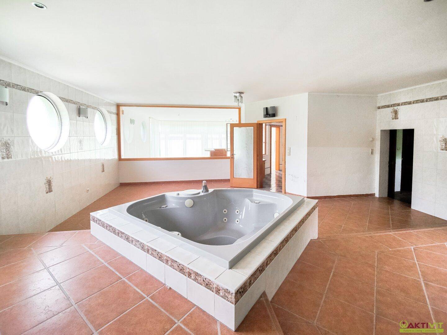 Großer Raum mit eingebautem Whirlpool und Terrakottafliesen, ideal für Entspannung und Erholung.