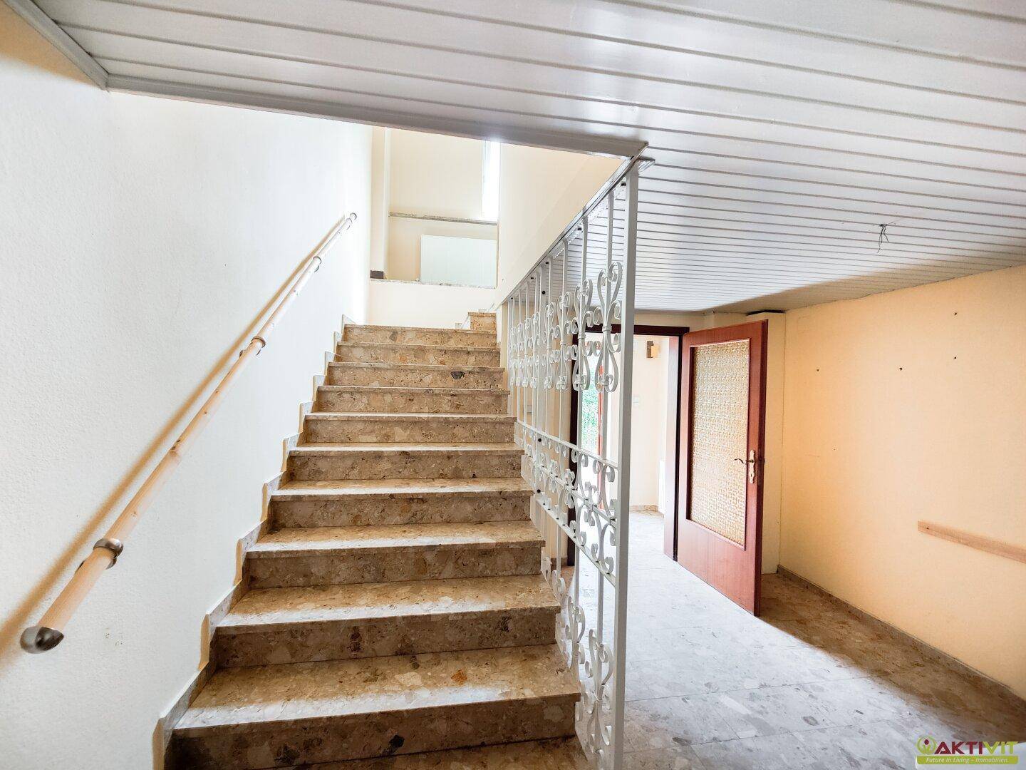 Treppenhaus mit Marmorstufen und dekorativem Geländer, das in die obere Etage führt.