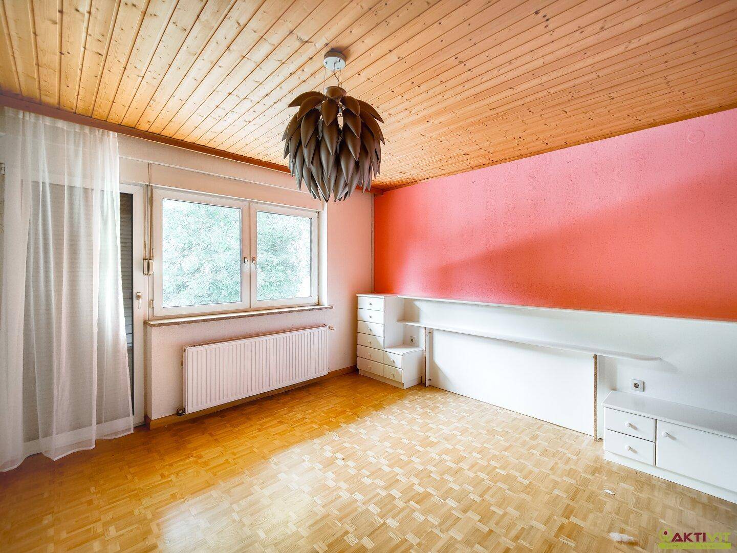 Schlafzimmer mit Holzdecke, rosa Akzentwand und Parkettboden, hell und einladend.