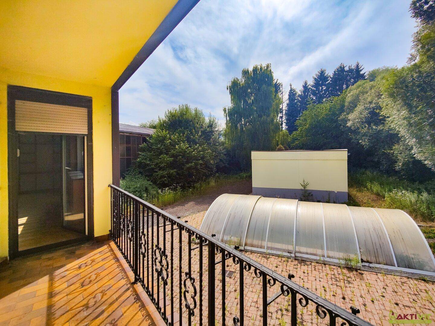 Balkon mit Blick auf den Außenbereich, einen überdachten Pool und die umliegende Natur.
