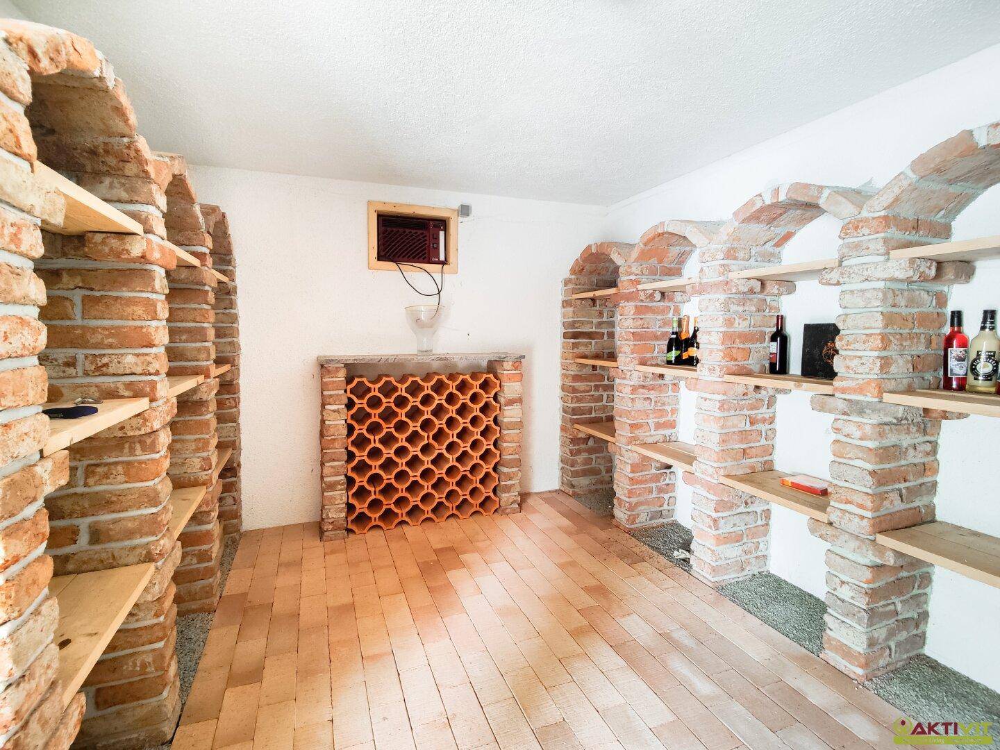 Rustikaler Weinkeller mit Ziegelgewölben, Holzregalen und Terrakotta-Fliesenboden für die Weinlagerung.